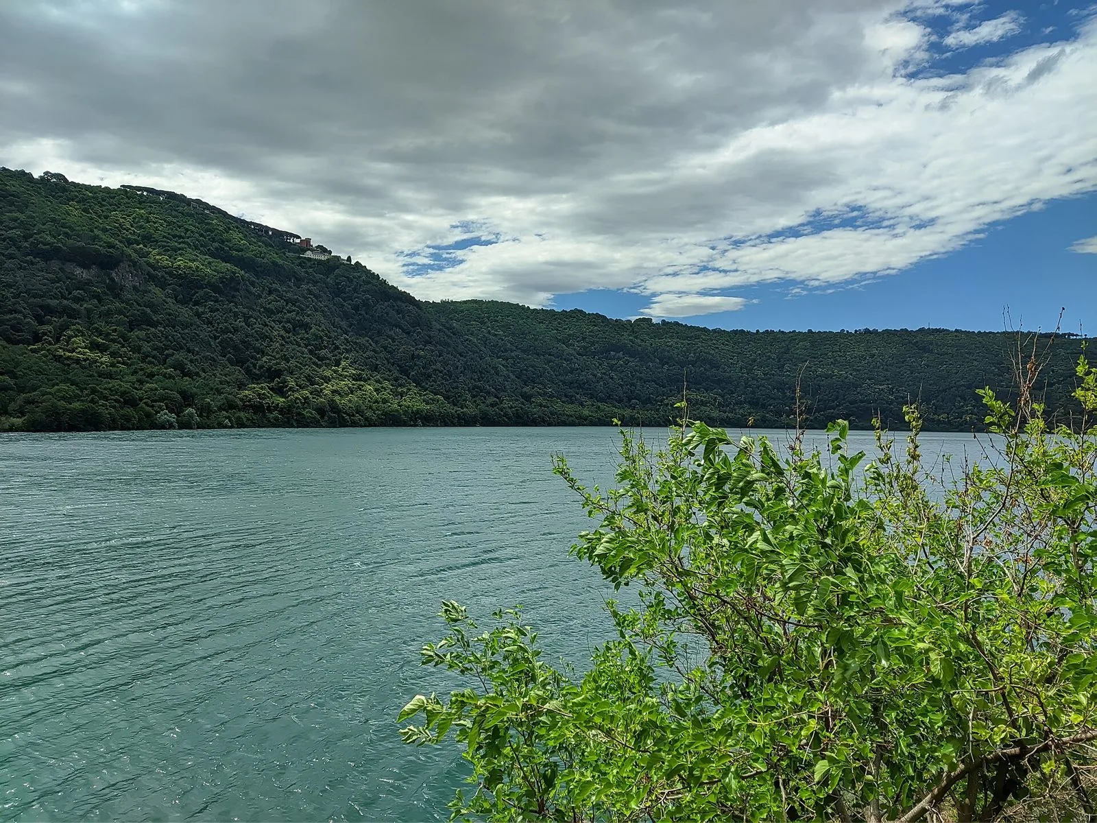 Il lago Albano con le sponde boscose e Castel Gandolfo in alto sulla collina